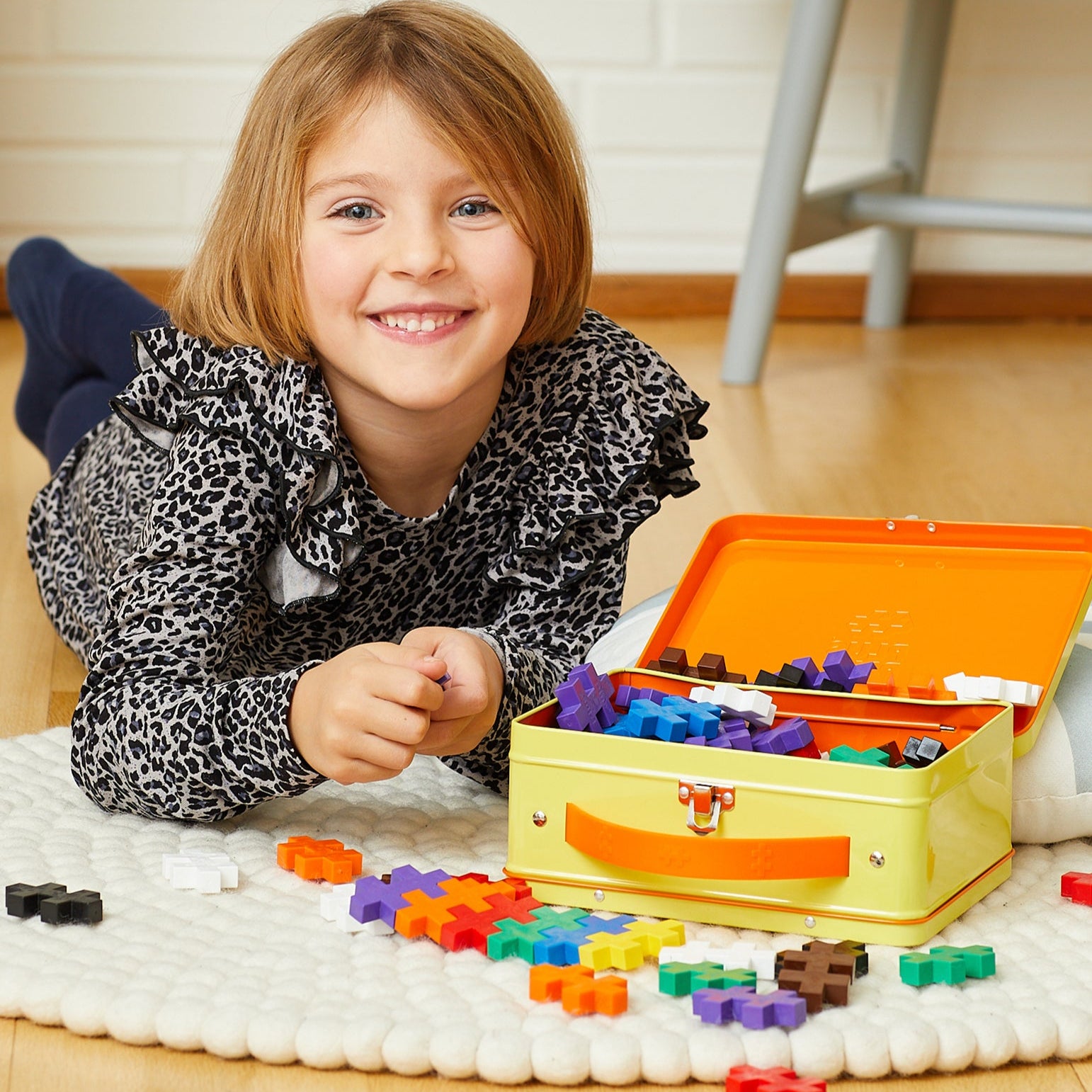 Child playing with colorful building blocks on a wooden floor